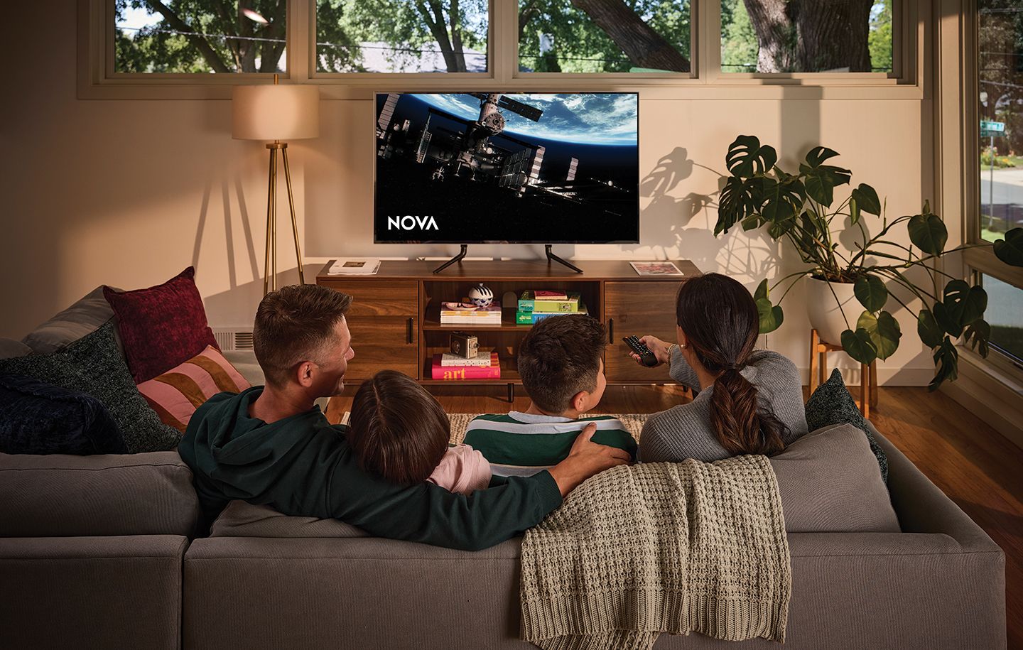 Family of four sitting on a couch watching the TV show NOVA from PBS