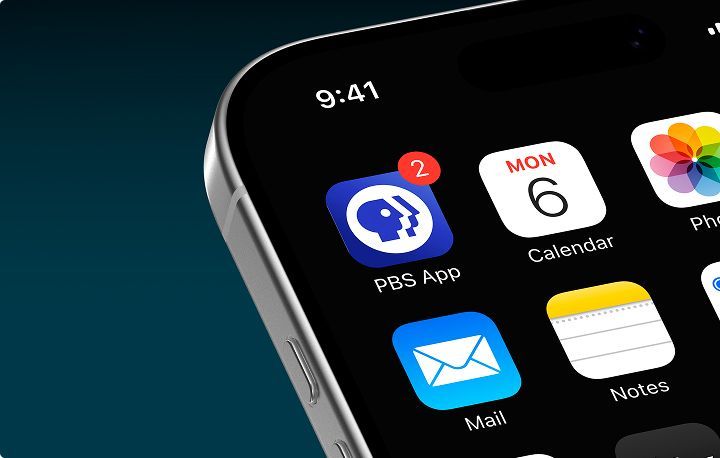 Close-up of a smartphone screen displaying app icons. Prominent is the PBS app icon, featuring a blue background with a white PBS logo and a red notification dot indicating two alerts. Other visible icons include Calendar, Mail, and Notes, showing a date of Monday, the 6th. The time displayed is 9:41. The background has a gradient dark color.
